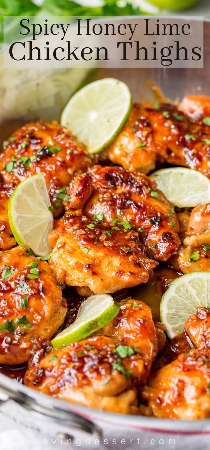A close up of chicken thighs in a spicy sauce with lime wedges