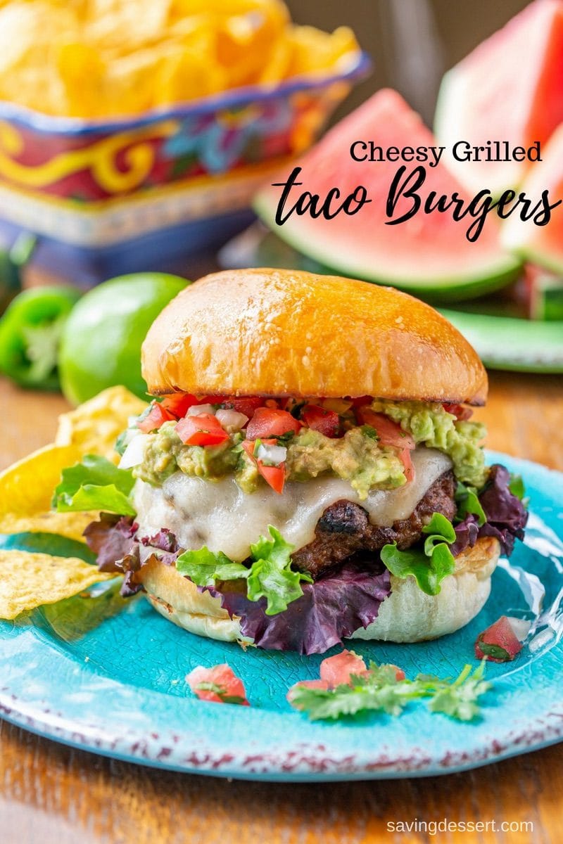 A cheesy grilled taco burger topped with guacamole, pico de gallo and lettuce