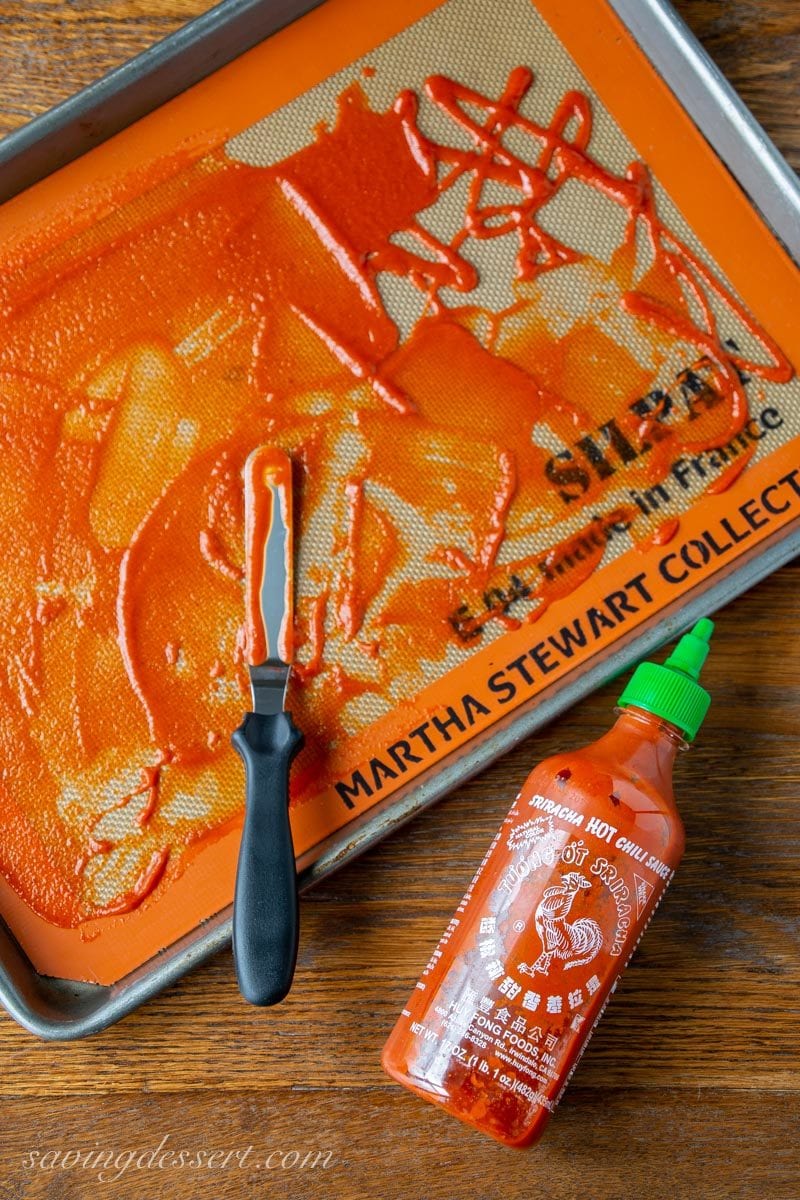 Sriracha Sauce spread on a silpat mat on a rimmed baking sheet