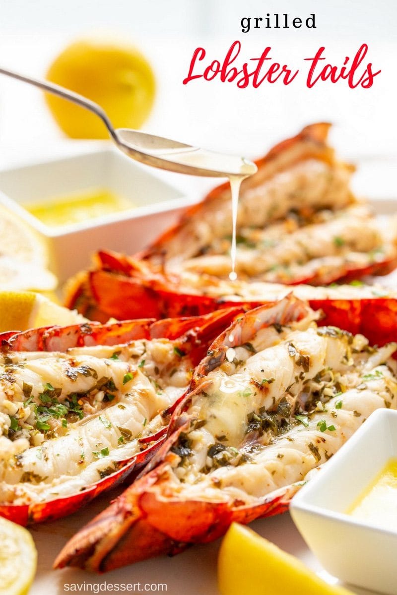 A platter of grilled lobster tails being drizzled with melted butter