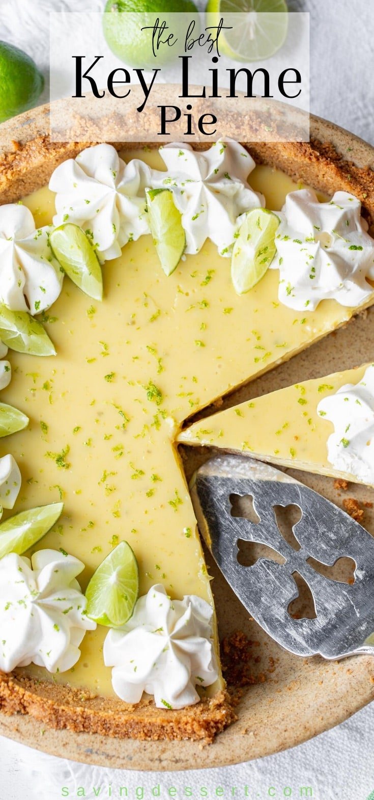 A sliced key lime pie decorated with fresh key limes and whipped cream