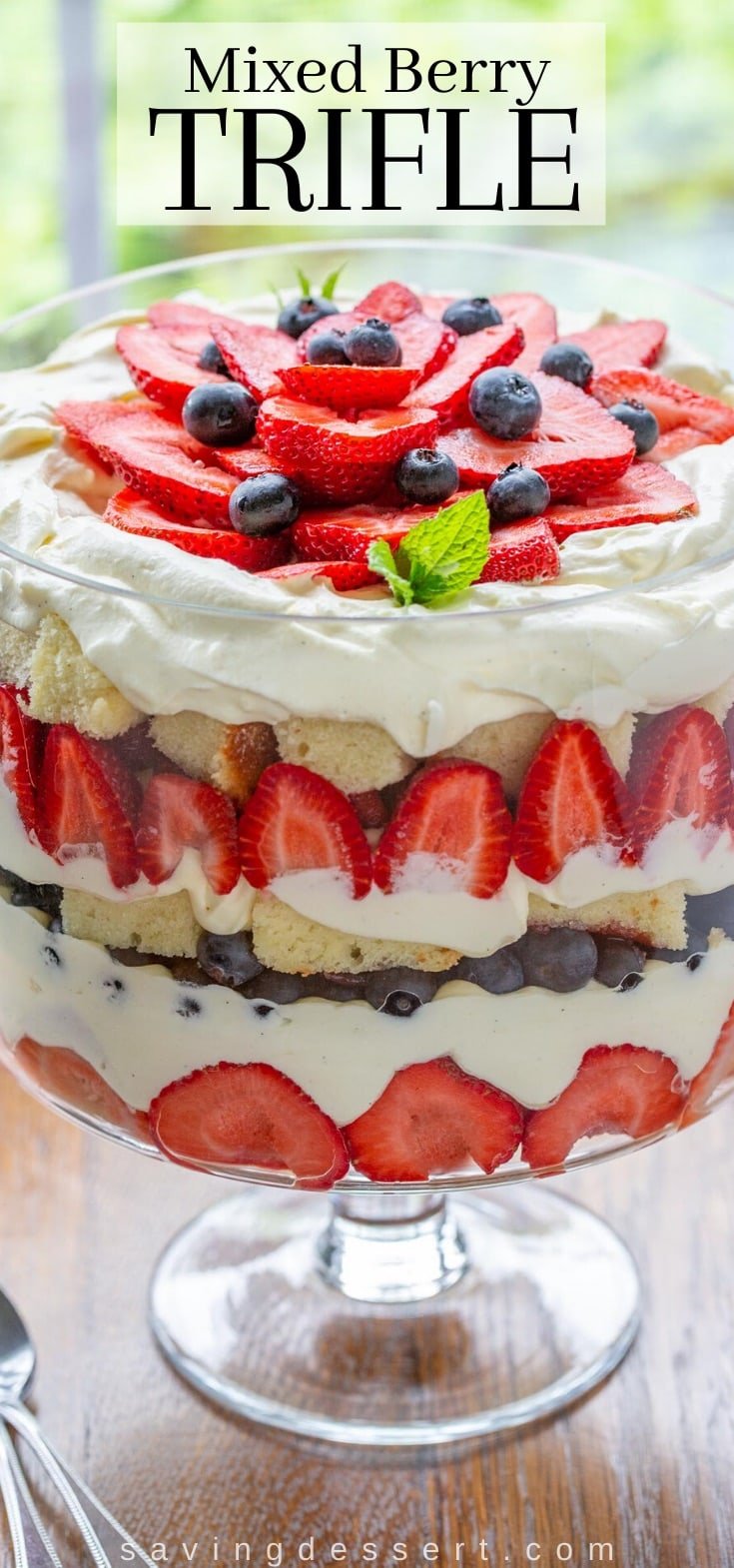 A trifle bowl filled with vanilla creamy, blueberries, strawberries and pound cake