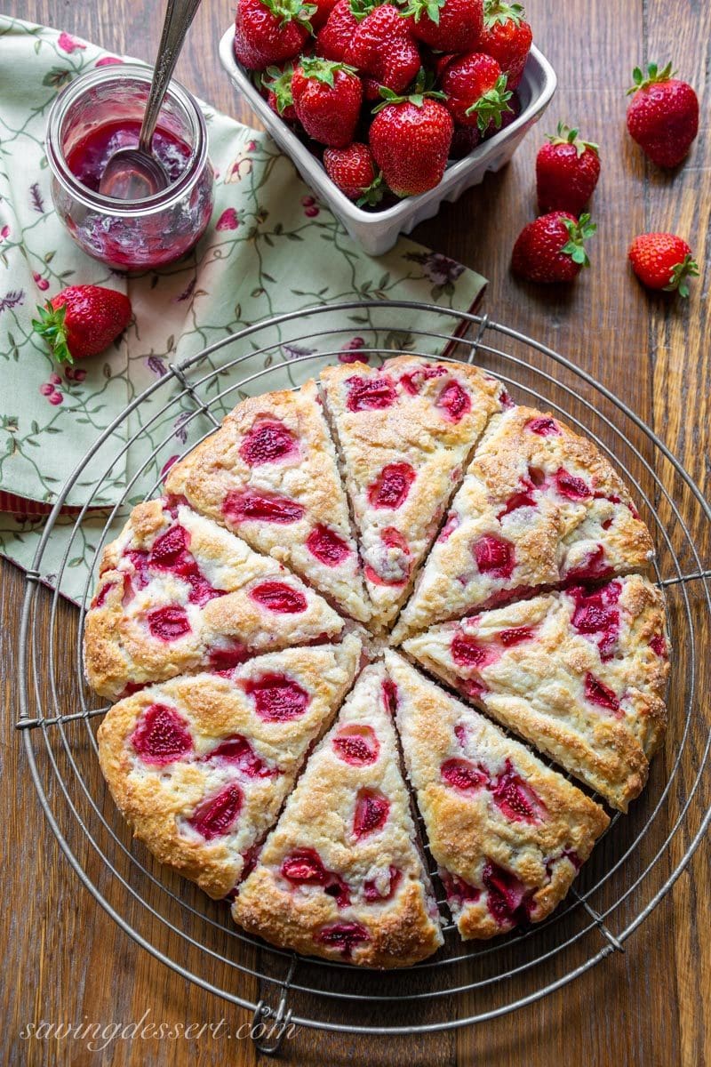 An overhead view of strawberry biscuits cut into wedges and served with strawberry jam