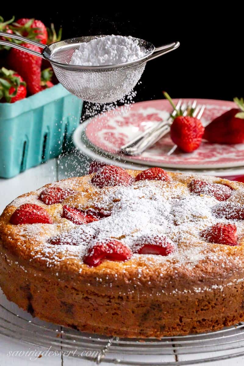 Single layer strawberry cake being dusted with powdered sugar
