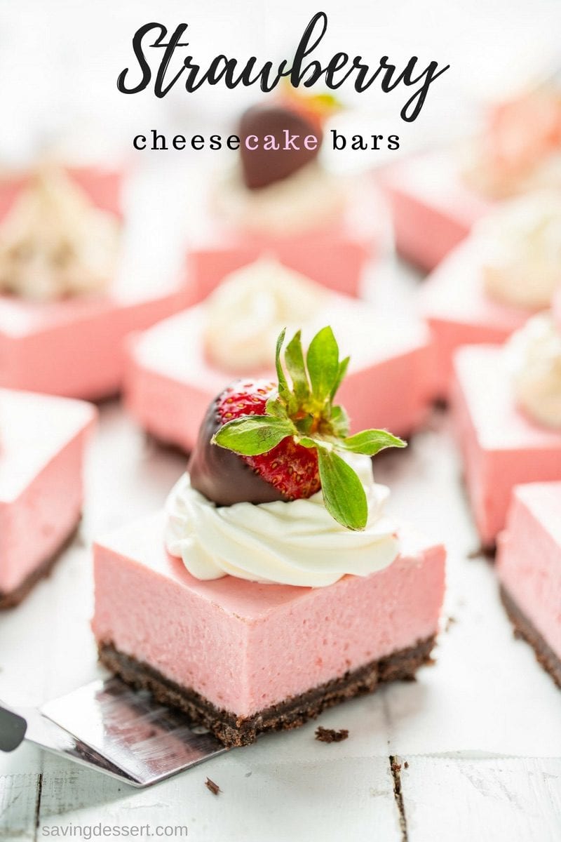 Strawberry cheesecake bars cut into squares topped with whipped cream and chocolate covered strawberries