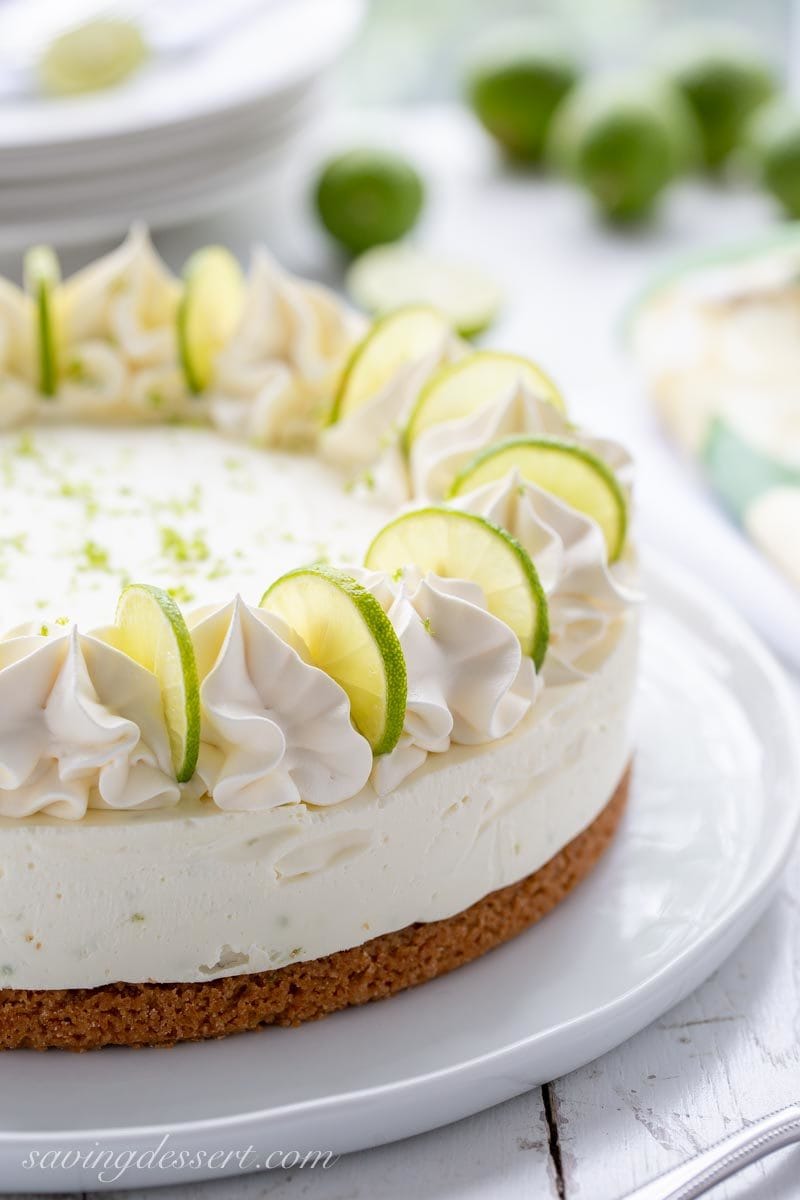 A side view of a no-bake key lime cheesecake garnished with key limes and whipped cream