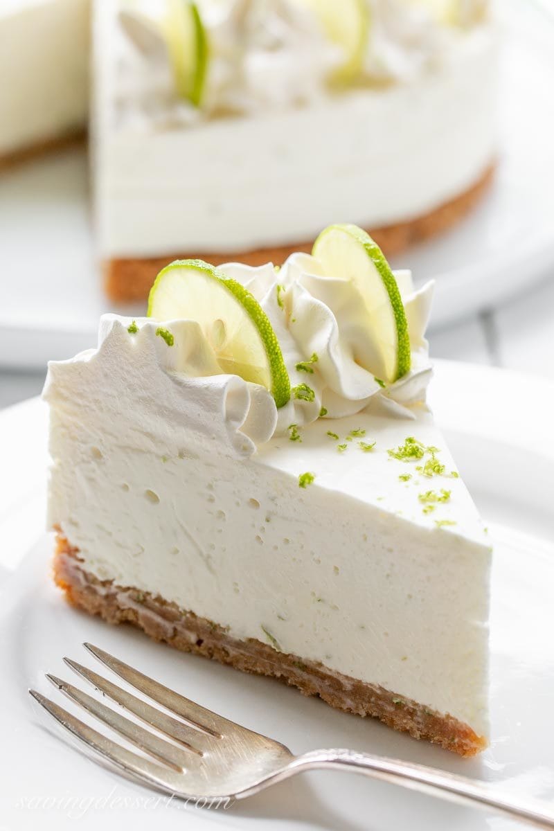 A slice of Key Lime Icebox Cheesecake decorated with cream cheese whipped cream, key lime slices and key lime zest