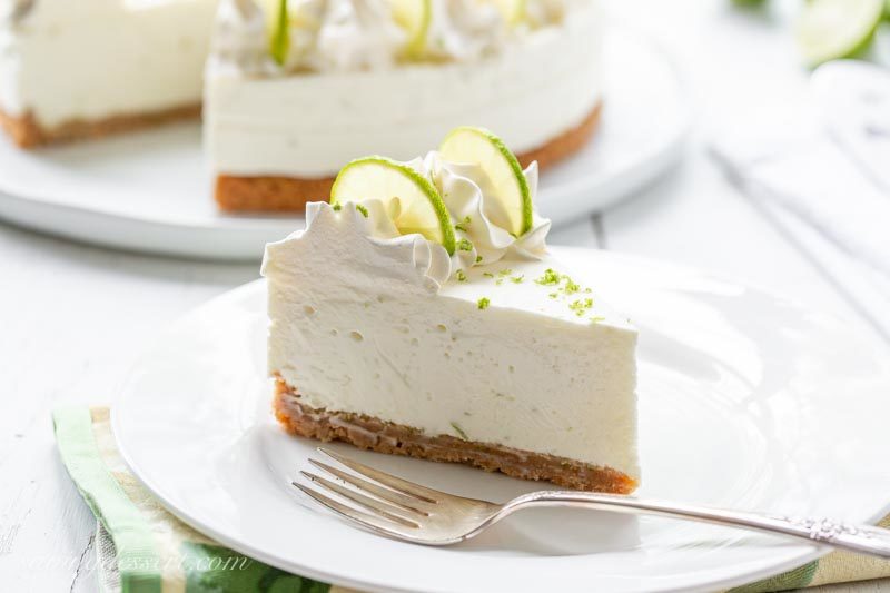 A slice of no-bake Key Lime Cheesecake with cream cheese whipped cream, key lime slices and key lime zest