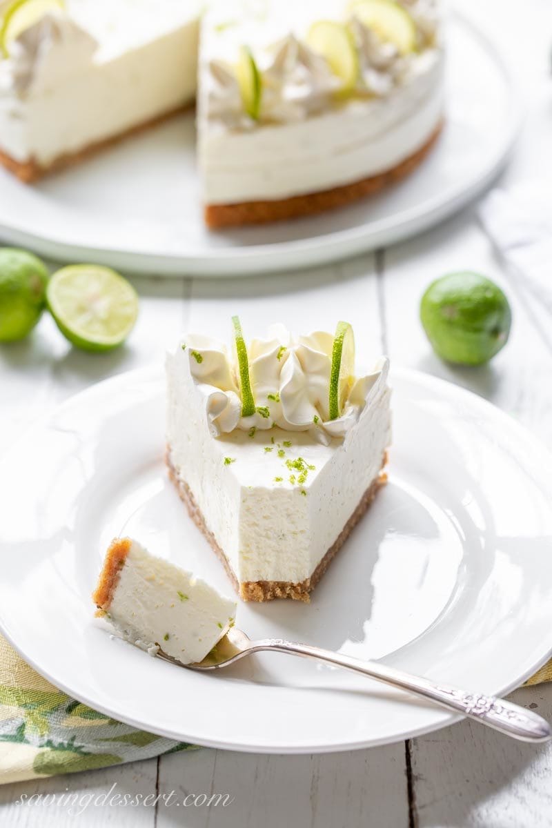 A slice of Key Lime Icebox Cheesecake decorated with whipped cream, sliced key lime slices and zest