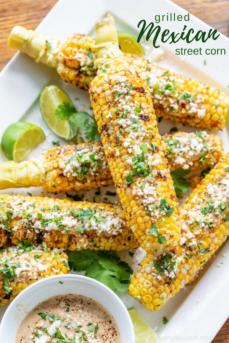 A platter of grilled Mexican Street Corn topped with cilantro and cheese