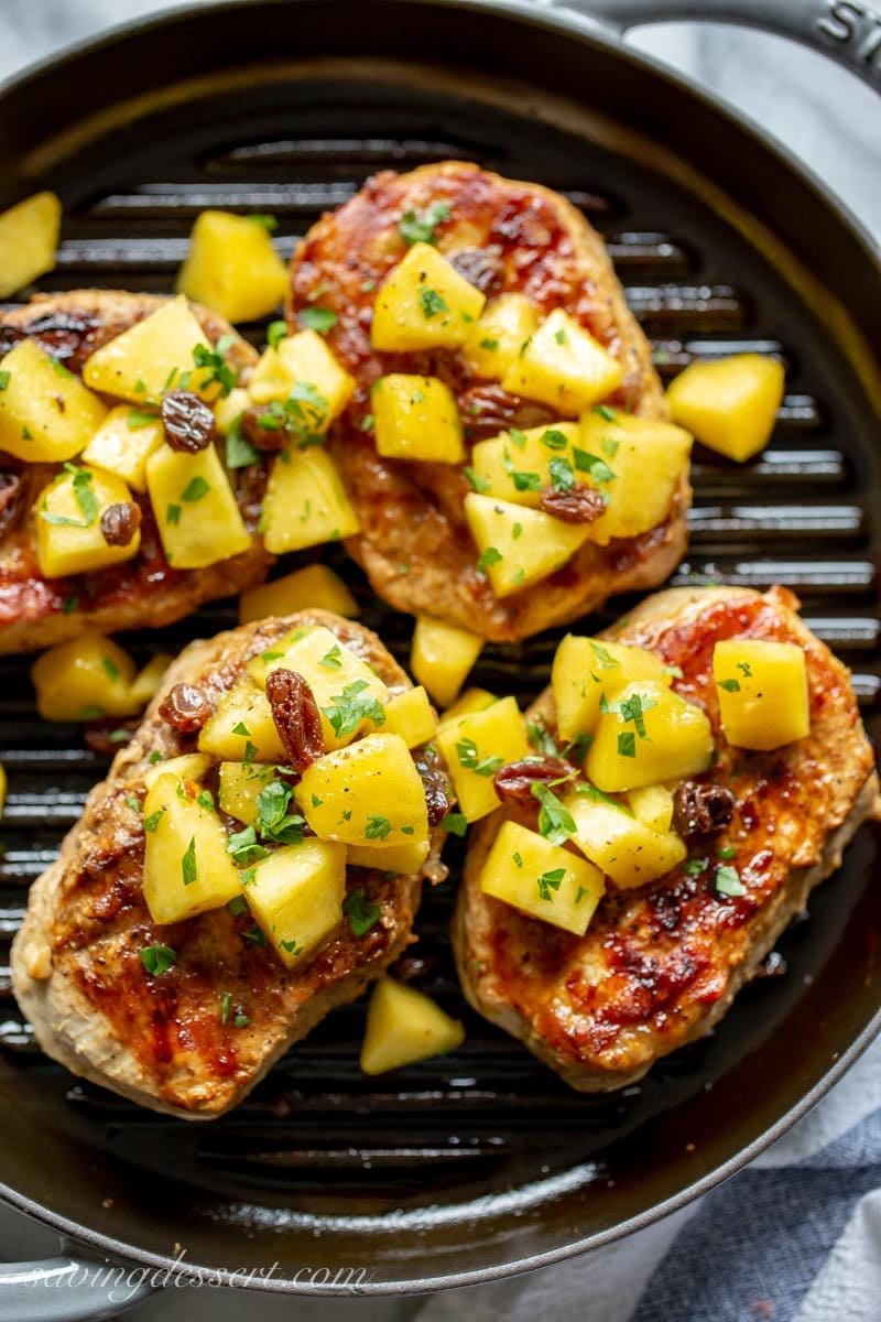 Close up of grilled pork chops topped with a peach and raisin sauce