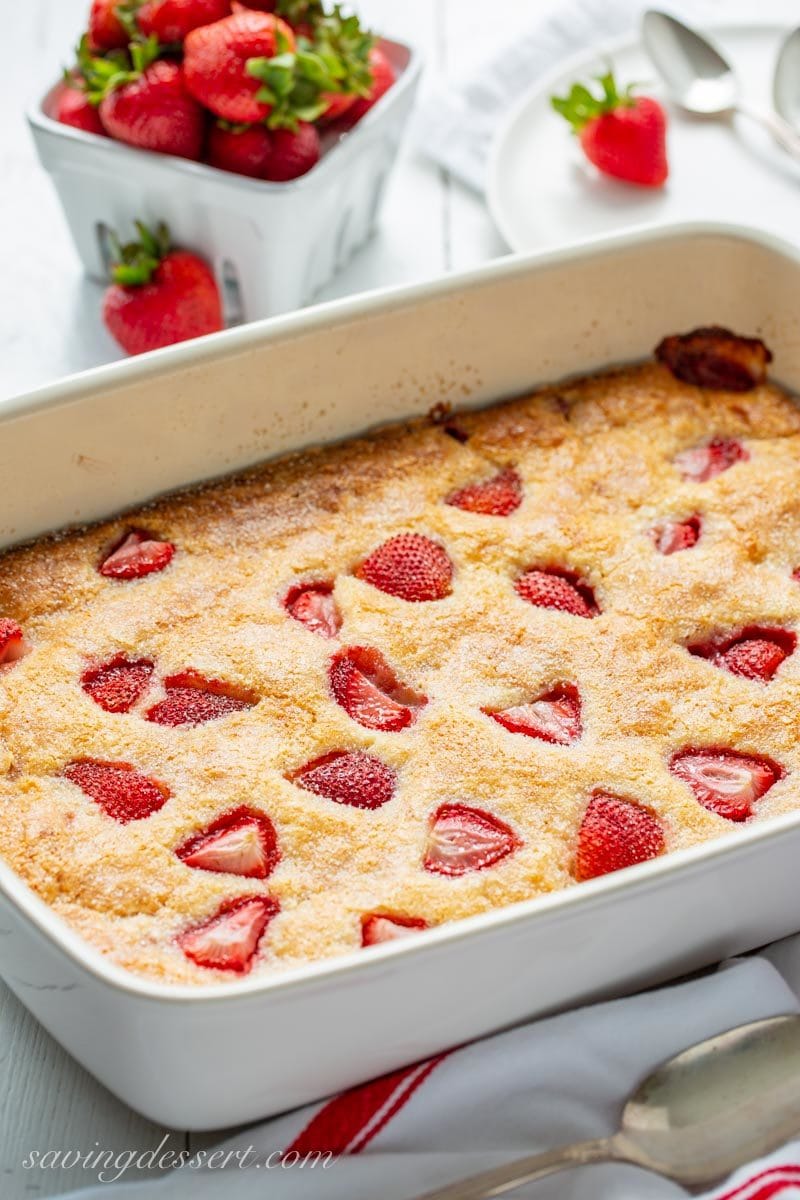 A casserole pan with a strawberry buckle topped with fresh strawberries