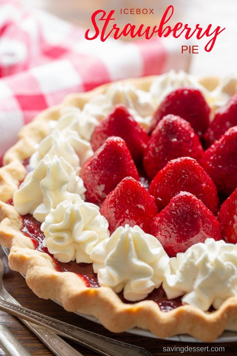 An icebox  pie with decorative whipped cream and whole strawberries in the middle