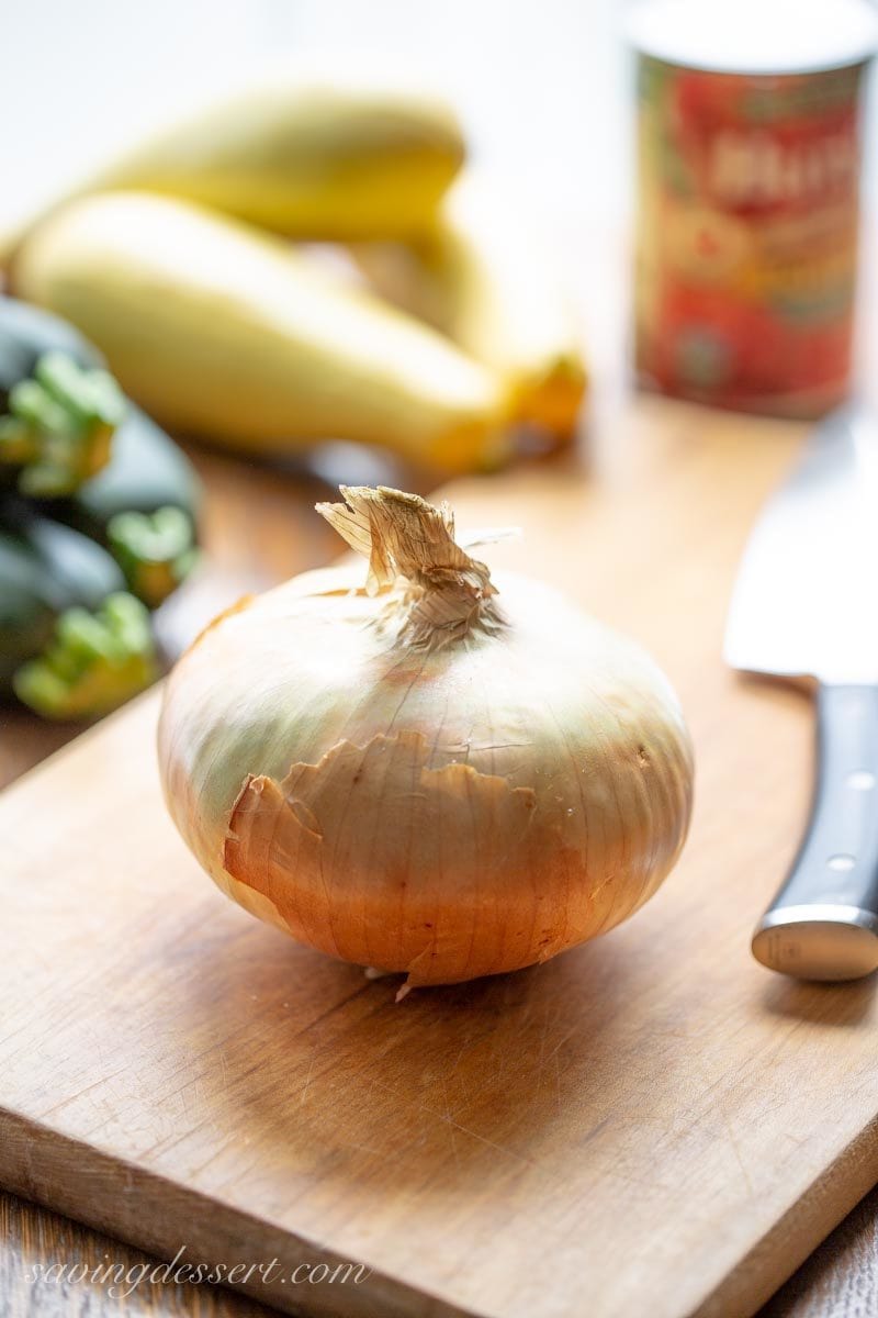 A large sweet onion, with zucchini, yellow squash and a can of tomatoes