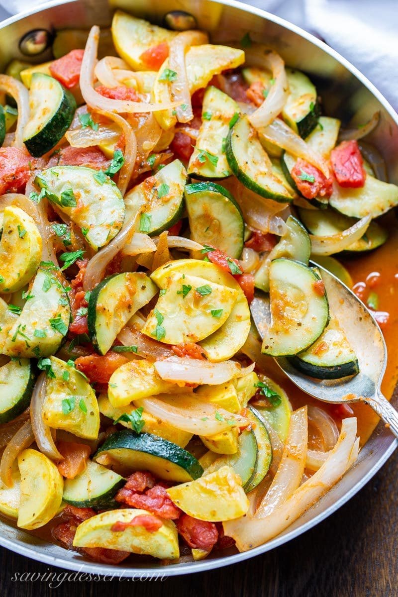 a skillet with summer squash, tomatoes and onions