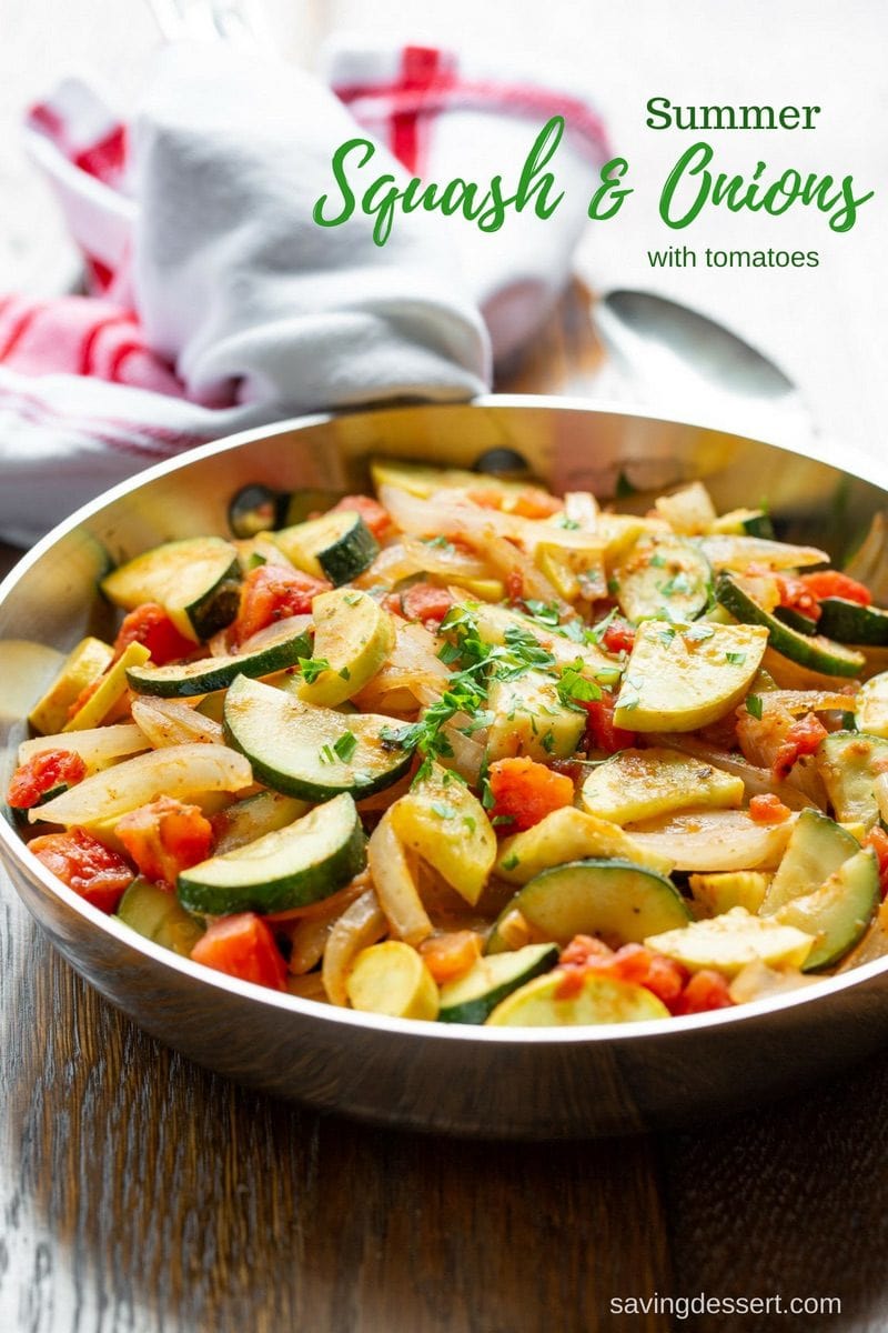 A skillet filled with summer squash and onions with tomatoes