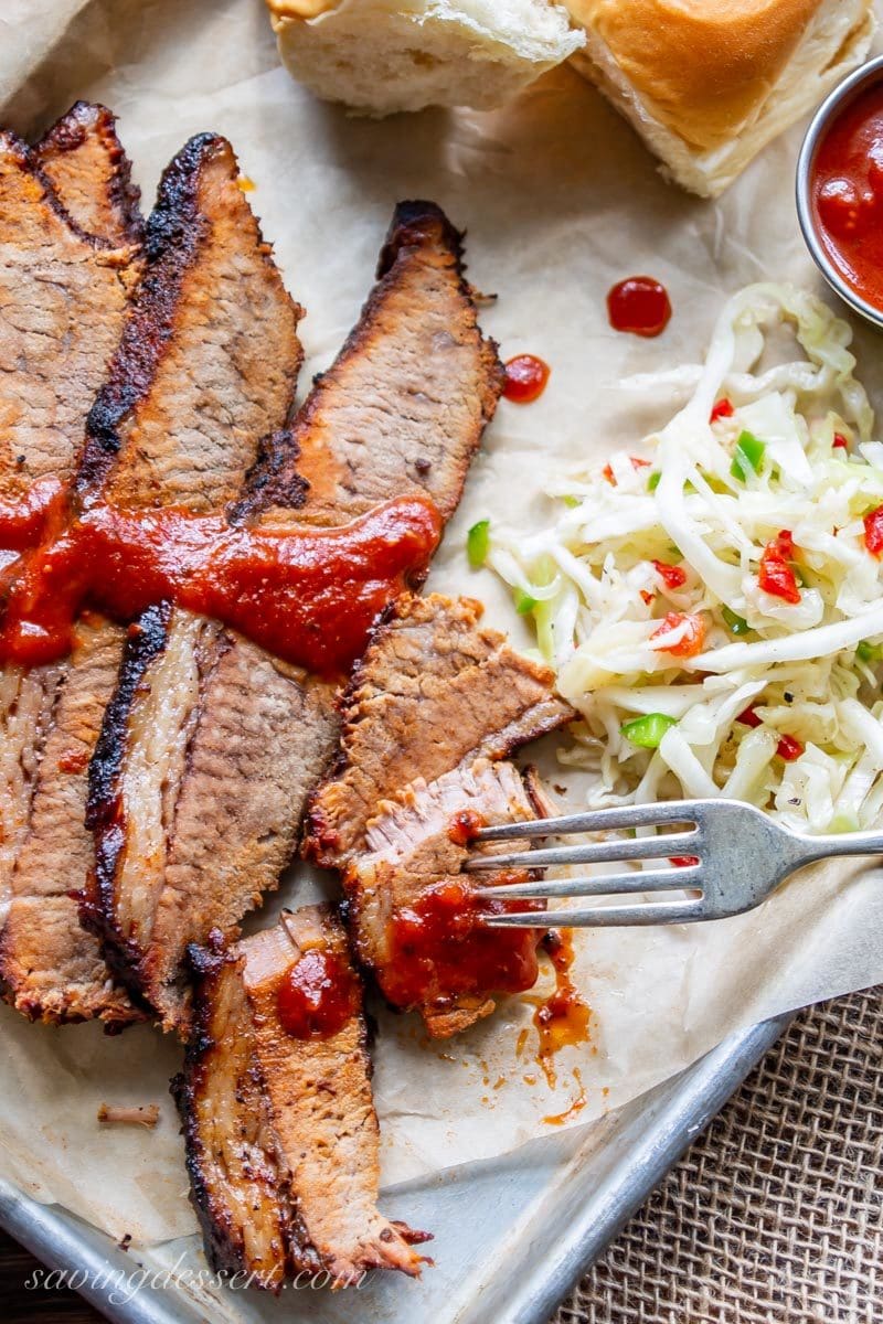 A pan of tender BBQ beef brisket with BBQ sauce and cole slaw