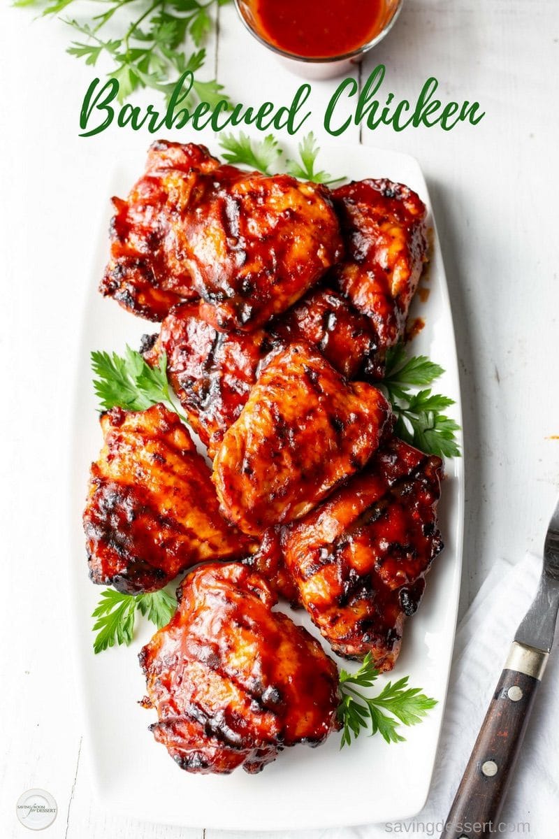 A platter of barbecued chicken pieces garnished with parsley