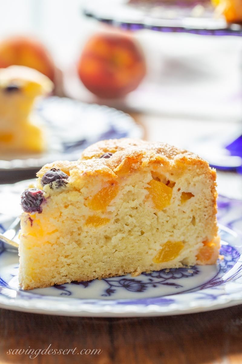 A big slice of fresh peach breakfast cake with a few blueberries