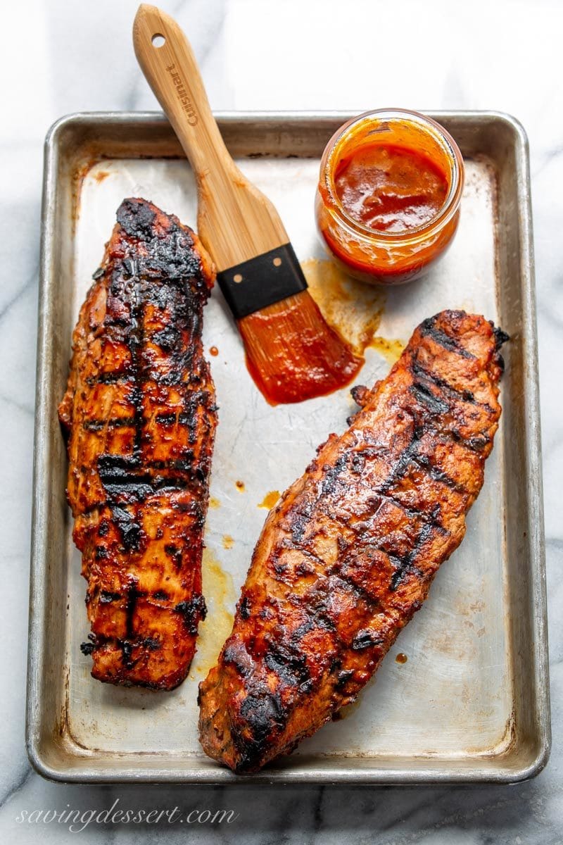 Two grilled pork tenderloins brushed with BBQ sauce 