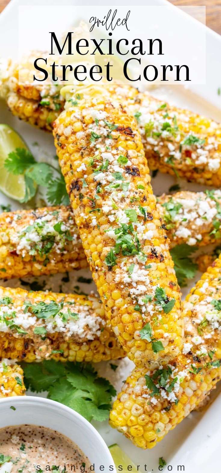 Grilled ears of corn topped with crumbled cheese and chopped cilantro on a platter