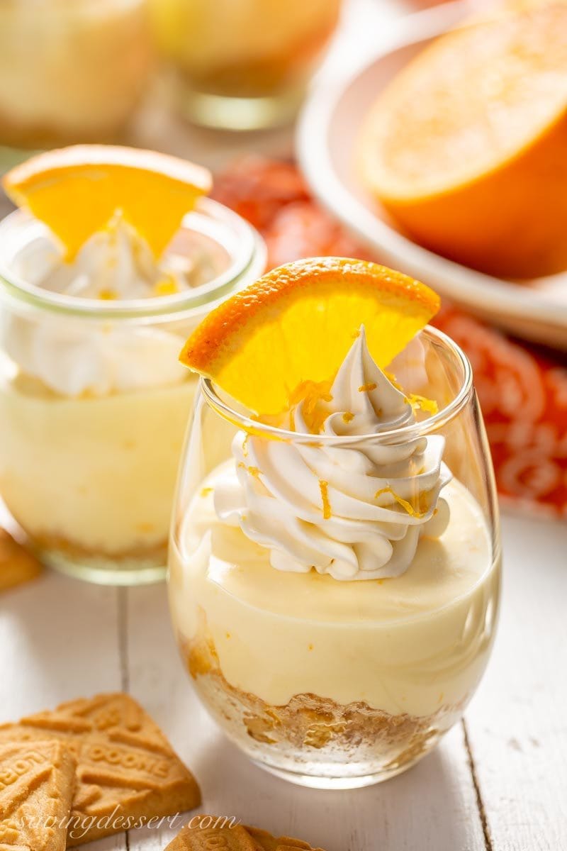 Orange Creamsicle No-Bake Cheesecake in jars with shortbread cookies and orange wedges