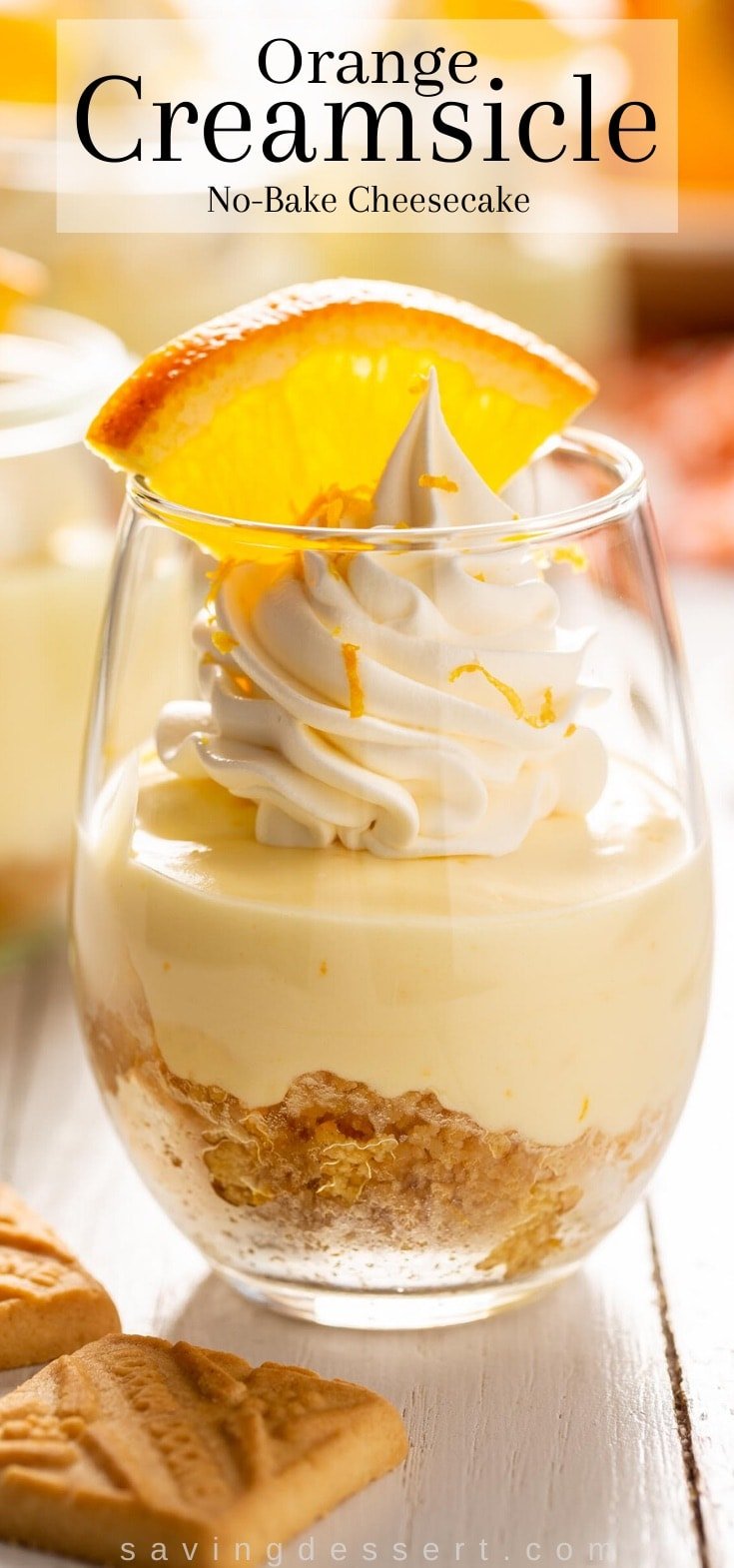 A small glass filled with orange creamsicle dessert topped with whipped cream and an orange slice