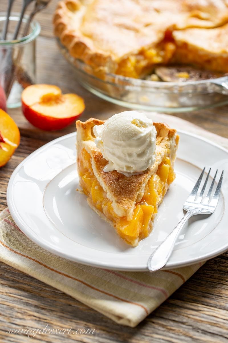 A slice of Old Fashioned Fresh Peach Pie with vanilla ice cream on top