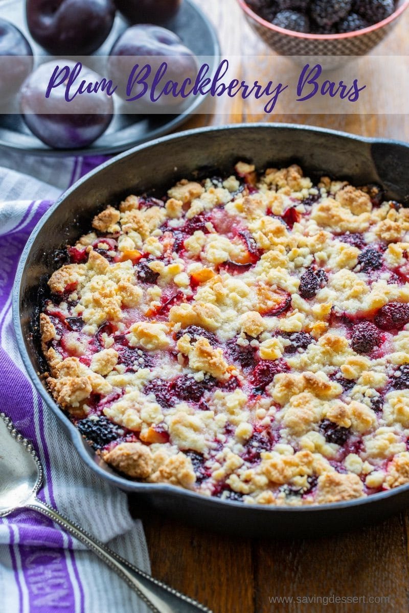 A cast iron skillet with plum and blackberry bars topped with a crumble crust