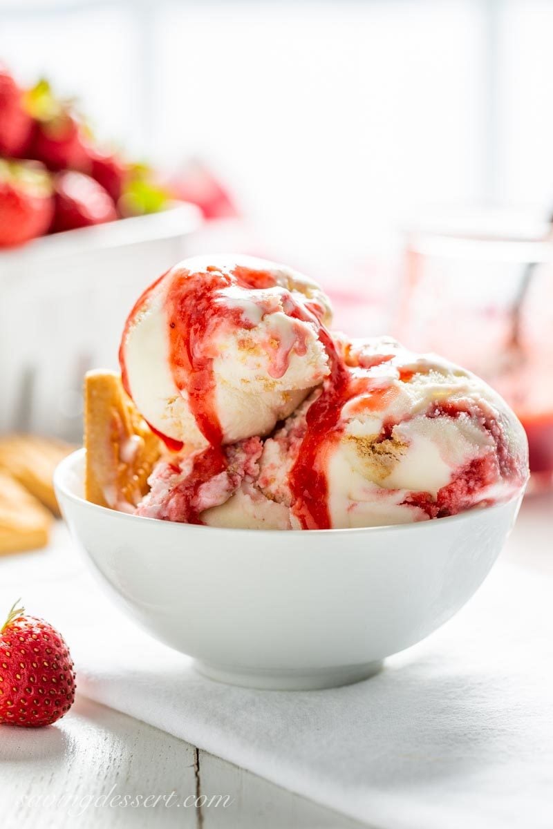 A bowl of strawberry shortcake ice cream with strawberry syrup and cookies