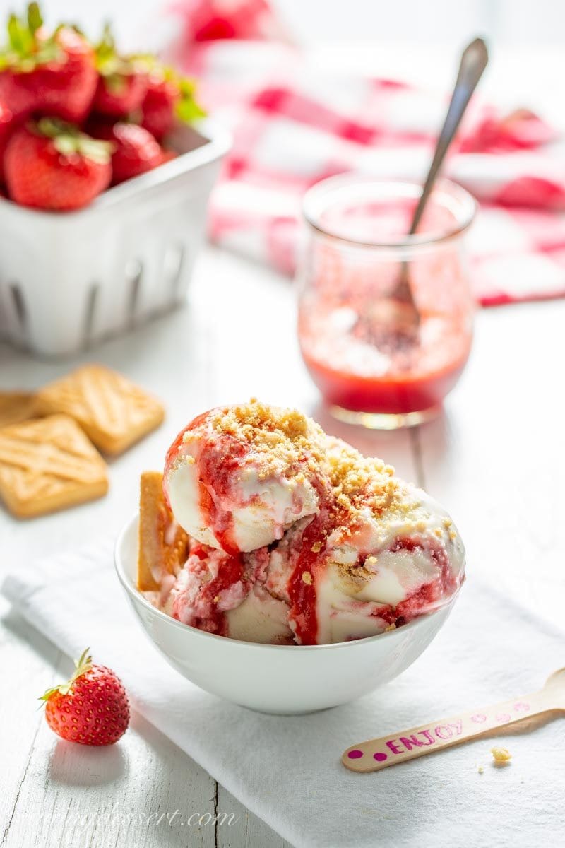 A bowl of Ice cream with strawberry sauce and crushed shortbread cookies on top
