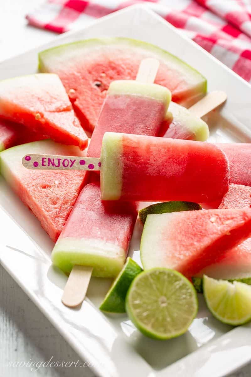 Sliced watermelon and watermelon popsicles with lime on a platter