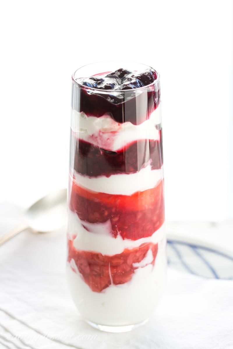 a tall glass of layered berry sauce and yogurt