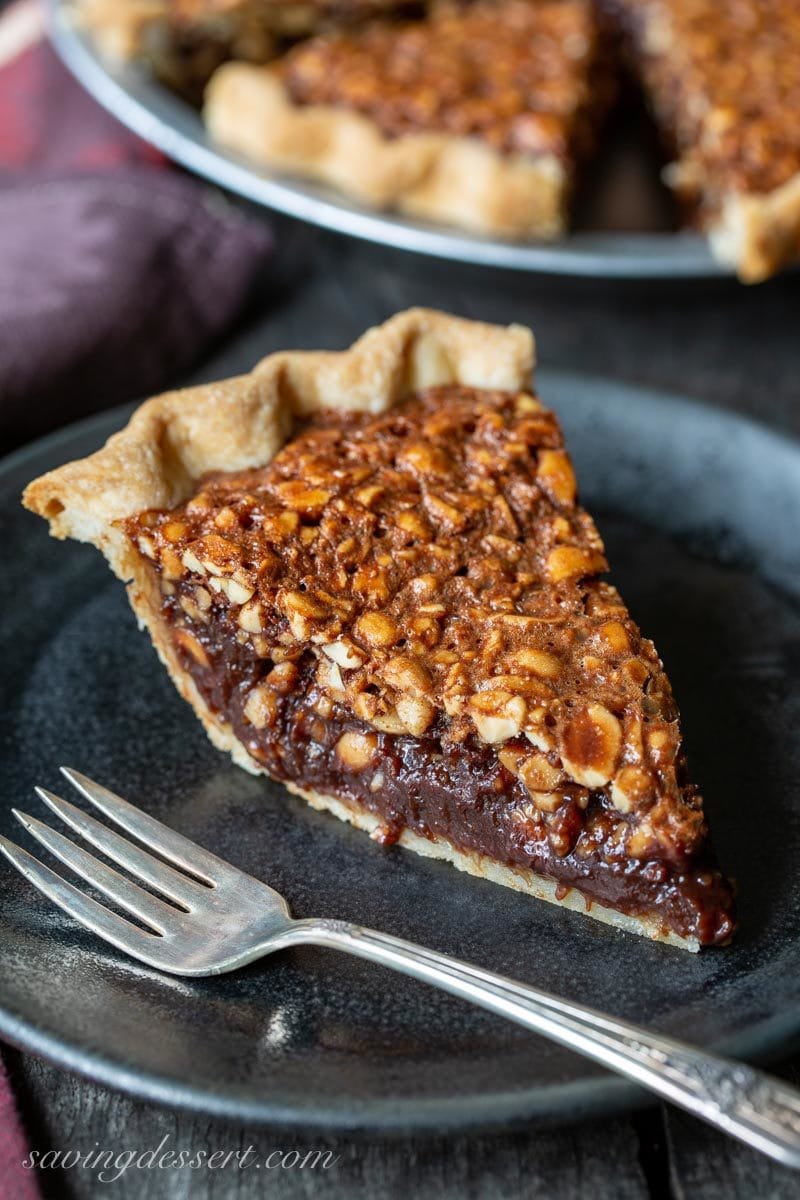 A slice of a fudgy peanut pie on a black plate