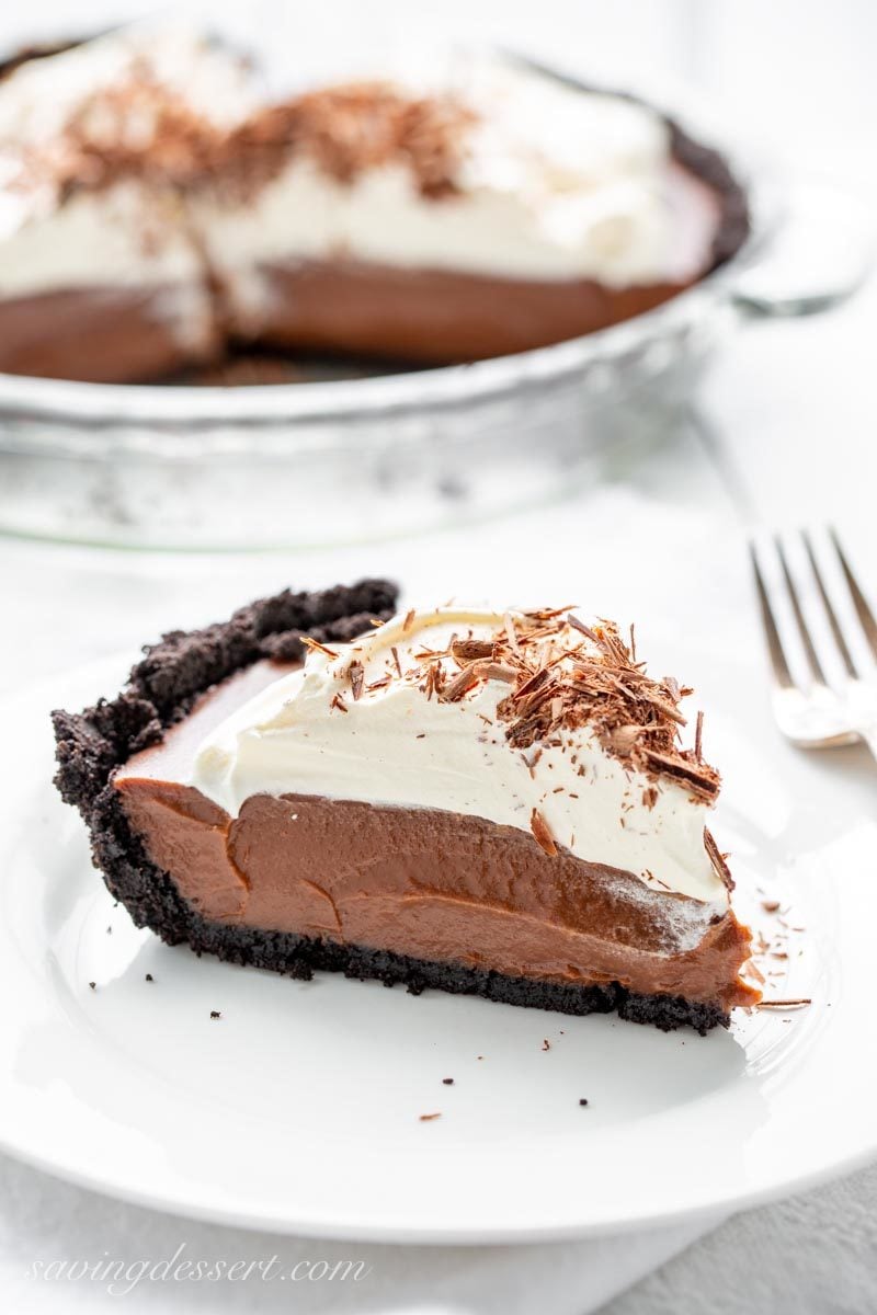 A slice of chocolate cream pie with whipped cream, chocolate shavings and a chocolate crust.