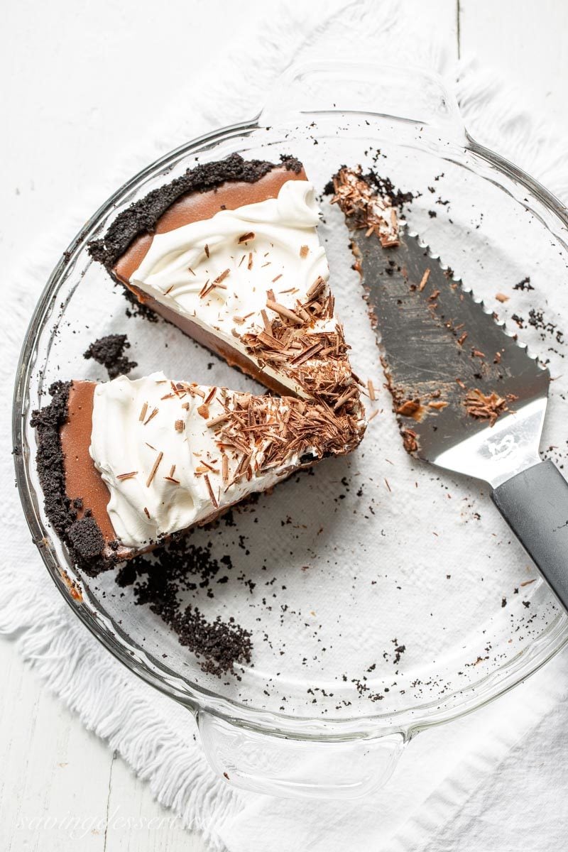 Two slices of chocolate cream pie topped with whipped cream and shaved chocolate curls