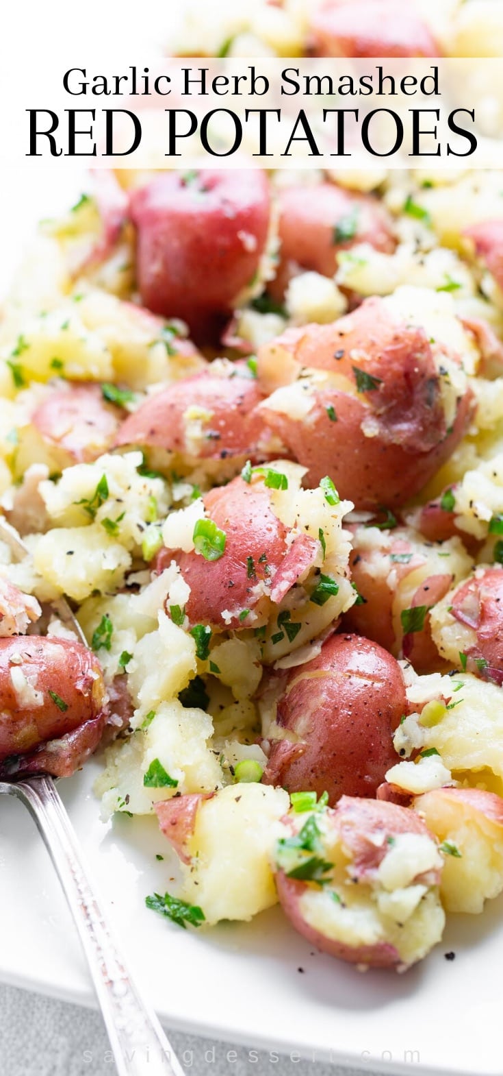 A plate of smashed red potatoes topped with herbs and green onions