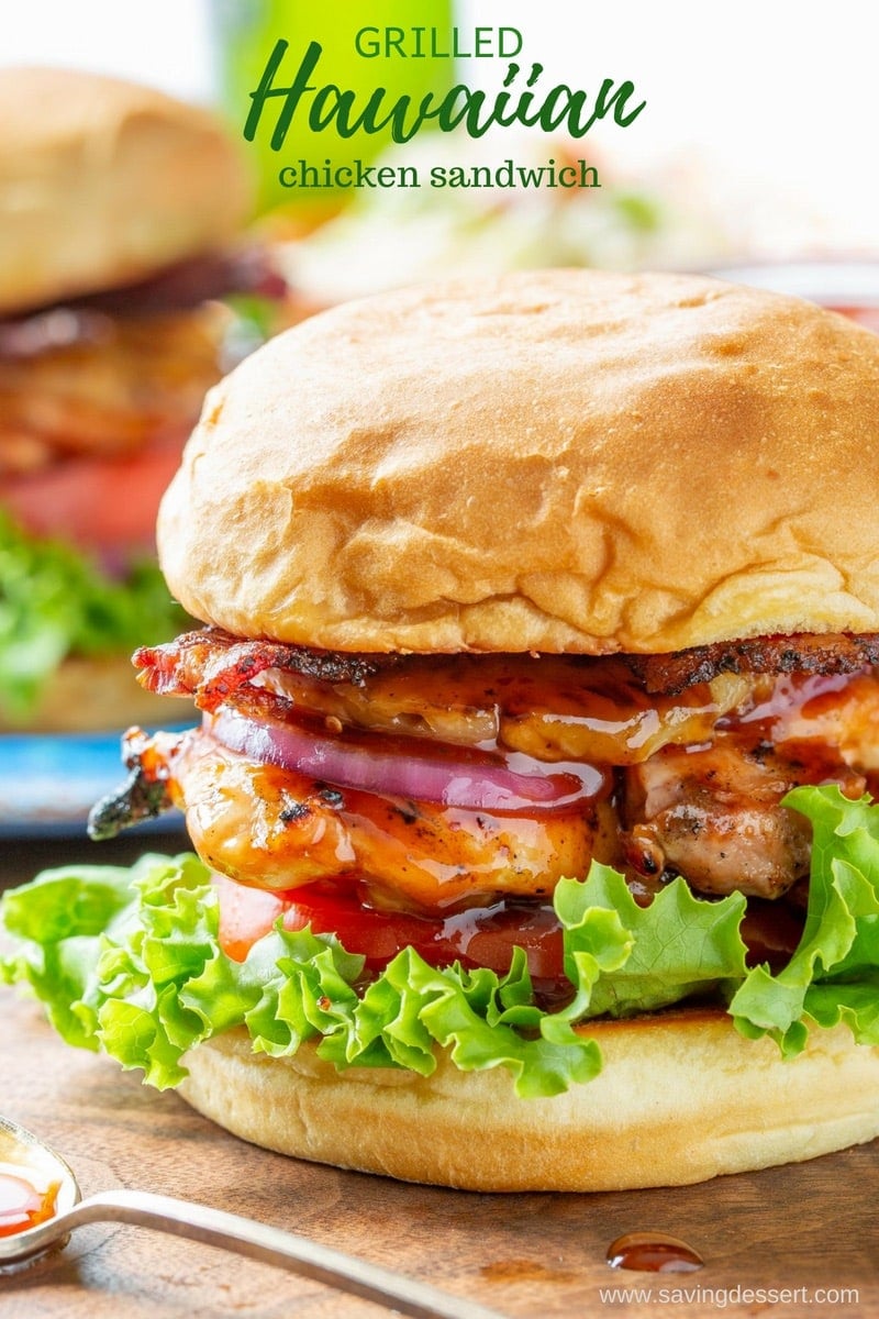 A grilled chicken sandwich with red onions, lettuce and tomato with BBQ sauce