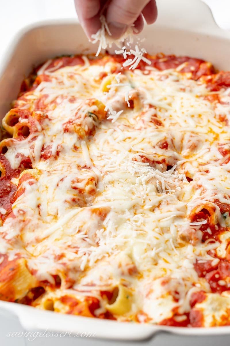 A large casserole dish with ricotta and spinach pasta bake, sprinkled with fresh grated Parmesan cheese.