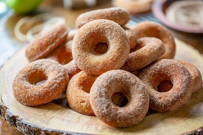 A stack of apple cider doughnuts on a wood platter
