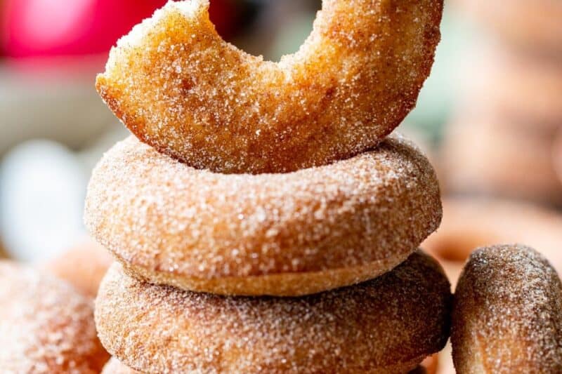 A stack of cinnamon sugar coated doughnuts with a half moon donut on the top