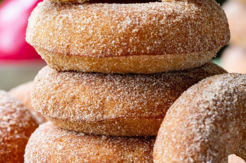 A stack of apple cider doughnuts on a cutting board