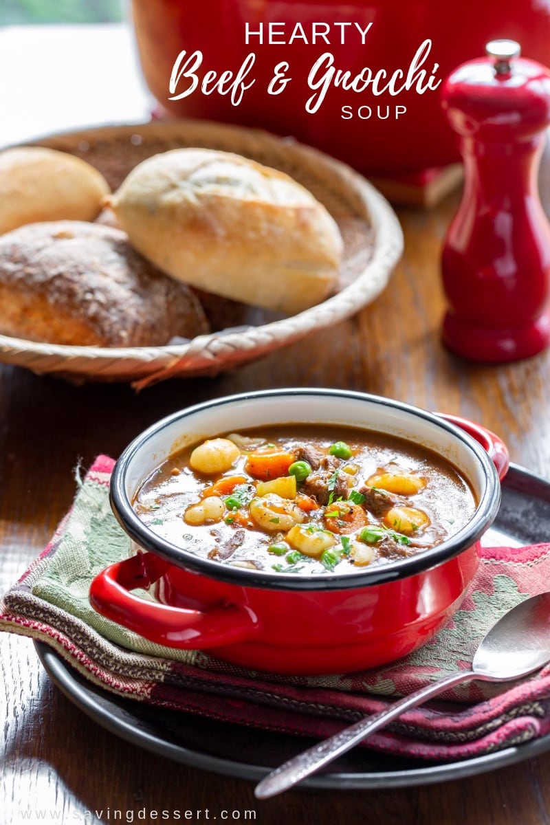 A table set with a bowl of soup, a soup pot and fresh baked rolls