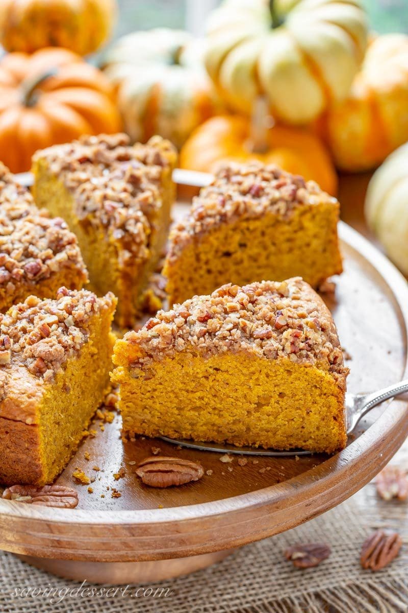 A sliced Pumpkin Breakfast Cake on a cake plate topped with a sweet Pecan Crumble