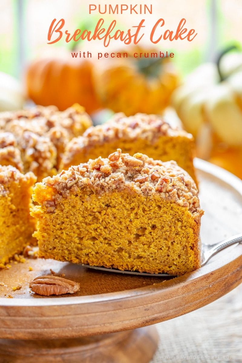 A sliced pumpkin cake on a cake stand with pecans