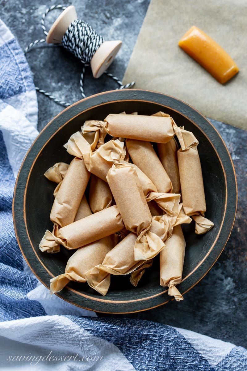 A bowl of apple cider caramels wrapped in brown parchment paper