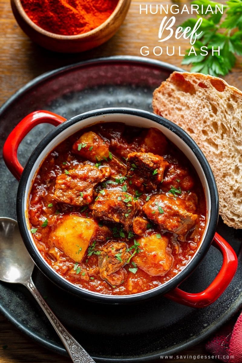A bowl of Hungary style beef Goulash served with bread and garnished with fresh parsley