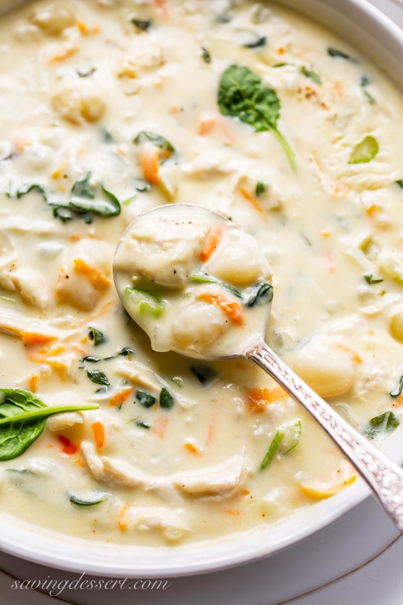 A spoonful of creamy chicken gnocchi soup with spinach and carrots