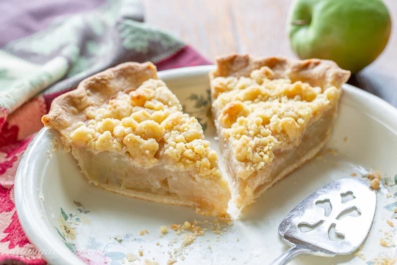 Two slices of Dutch apple pie in a pie plate with a spatula