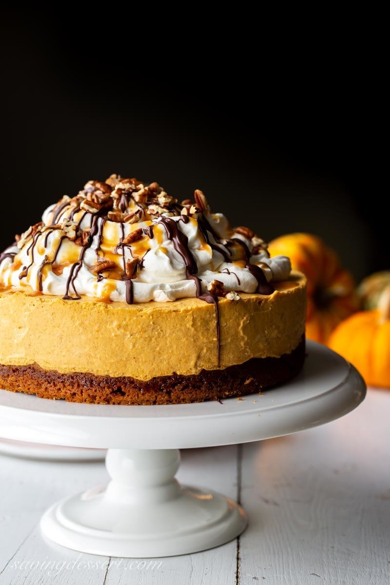 A no bake pumpkin cheesecake on a gingersnap crust topped with whipped cream cheese topping, caramel and chocolate drizzles and toasted pecans.
